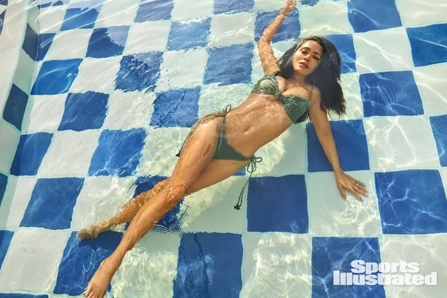 Salma Hayek floating in a tiled swimming pool in a green swimsuit.