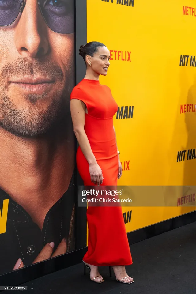Adria Arjona wearing a red dress and pale heels at a film event.