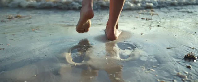 Daisy Edgar-Jones walking barefoot through shallow water.