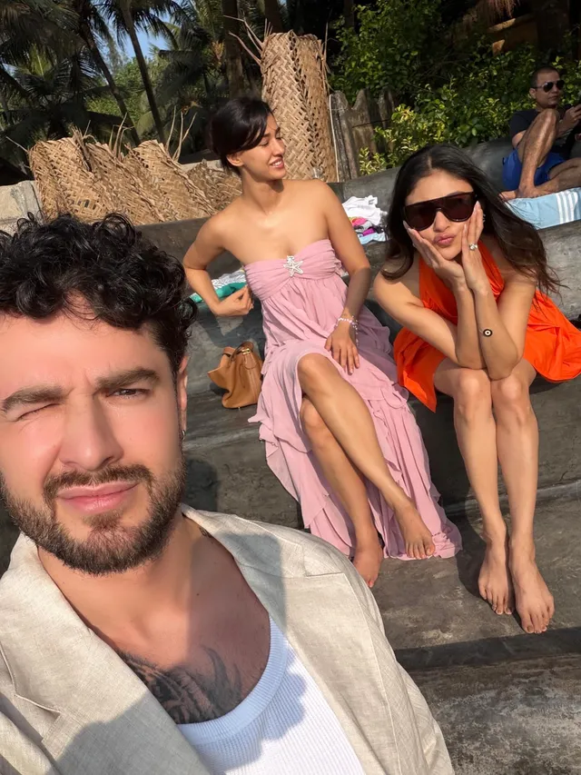 Disha Patani sitting barefoot with companions on outdoor steps.