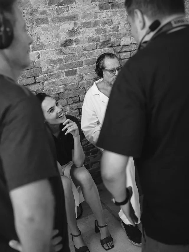 Gal Gadot sitting on a chair in black heels during an interview.