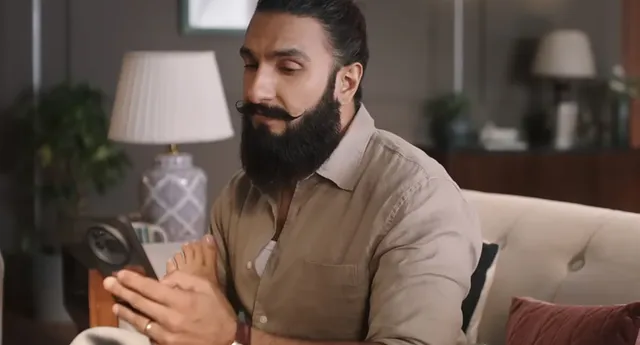 Deepika Padukone resting her bare foot beside a seated companion in a close-up screen scene.