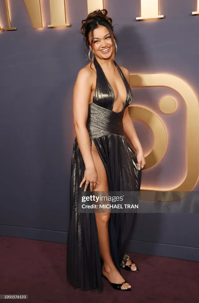 Madison Bailey posing in a black gown and black heels at an event.