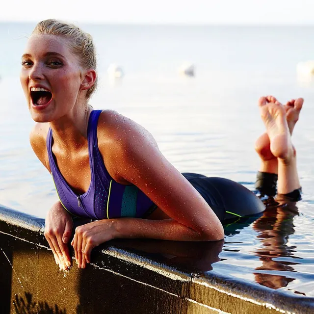 Elsa Hosk leaning on a swimming-pool edge with her bare feet raised.