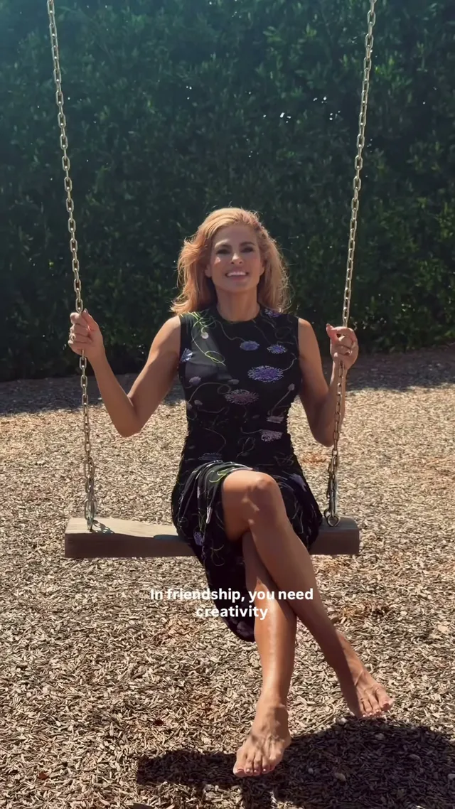 Eva Mendes sitting on a garden swing in a dark dress.