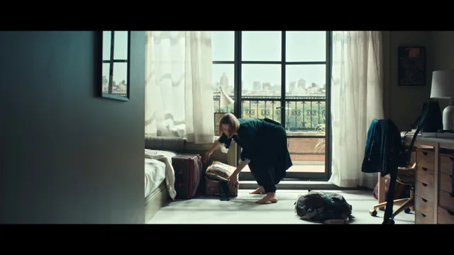 Jessica Biel seated beside a bed in a sunlit screen scene.