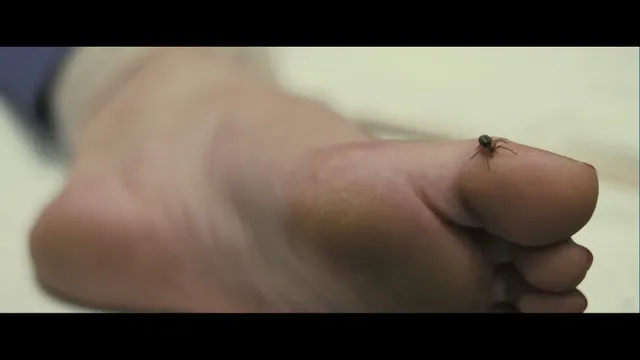 Gemma Arterton resting a bare foot on bedding in a screen scene.
