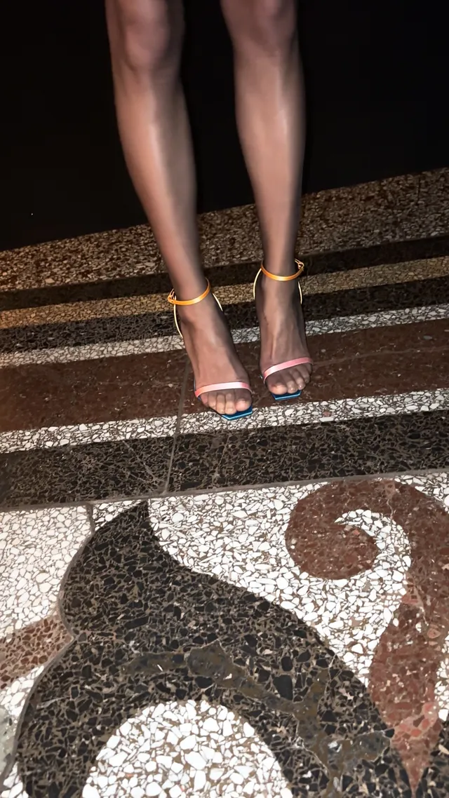 Zoë Kravitz wearing colourful sandals on sunlit steps.