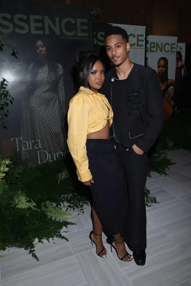 Ryan Destiny posing with a man in a yellow cropped top, dark skirt and black heels.