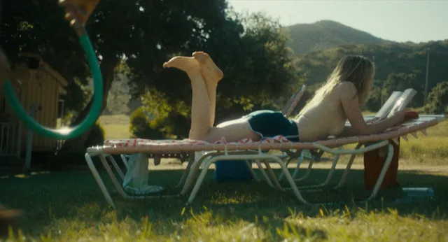 Kiernan Shipka lying on a sun lounger with her bare feet raised.