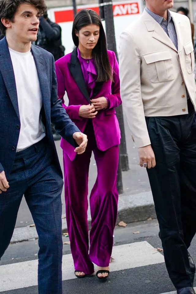 Anya Chalotra walking beside a man in a purple trouser suit and heels.