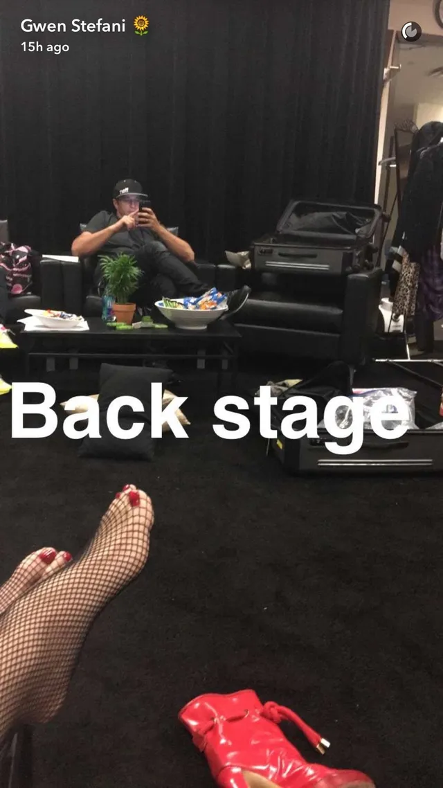 Gwen Stefani resting feet in fishnet tights backstage.