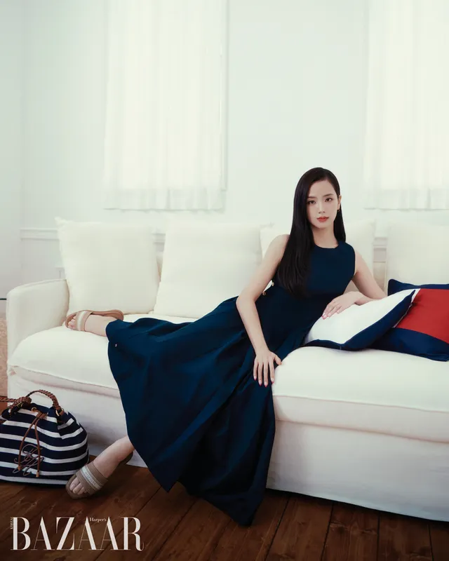 Jisoo reclining on a sofa in striped flat slides and a long blue dress.