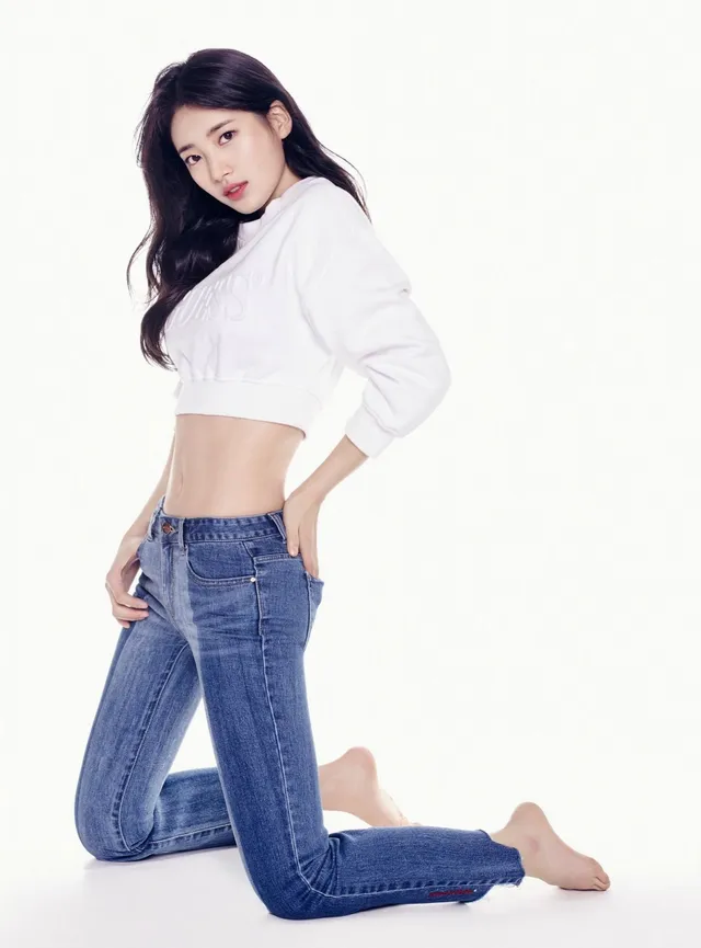 Bae Suzy kneeling barefoot in jeans and a white top.