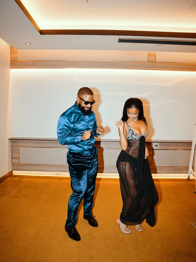 Tyla posing beside a companion in pale heels and a dark outfit indoors.