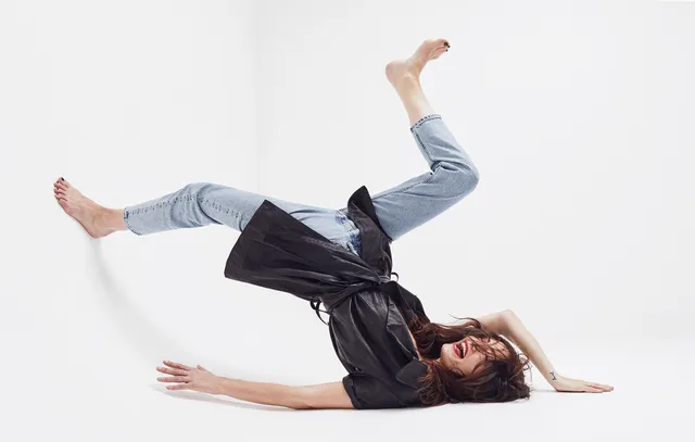 Phoebe Tonkin posing on the studio floor in jeans.