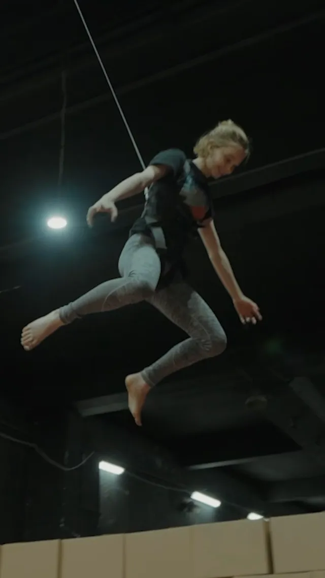 Emma Myers jumping barefoot in a gym training scene.
