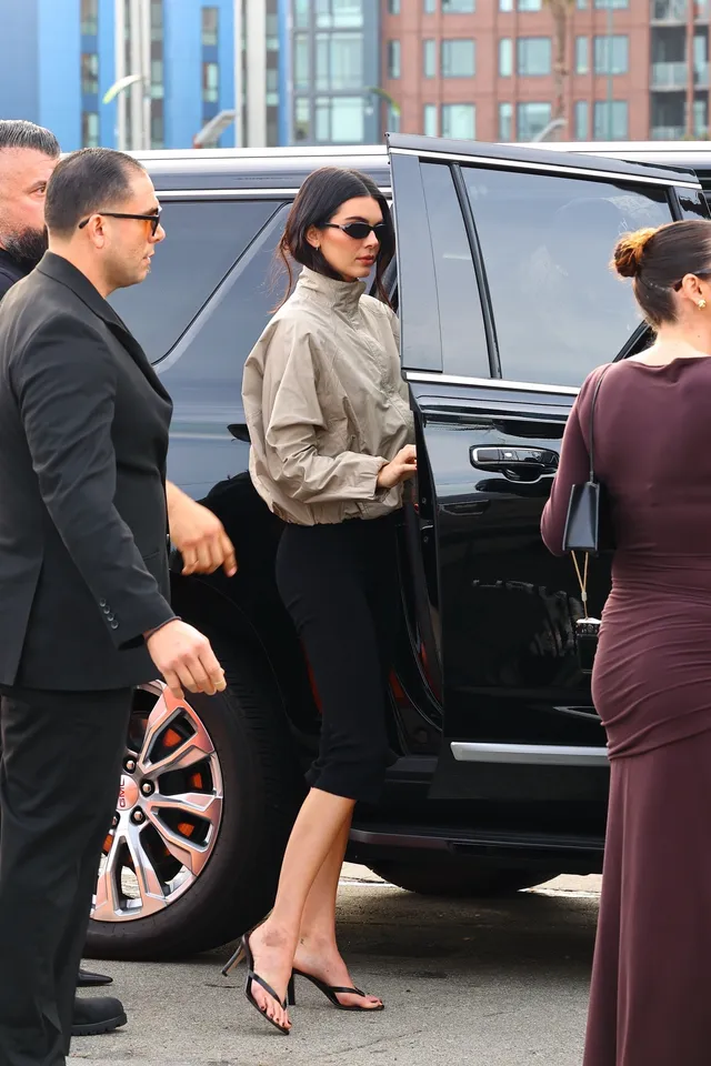 Kendall Jenner standing by a vehicle wearing black heels.