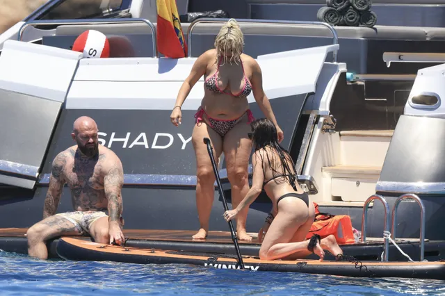 Bebe Rexha standing barefoot on a boat platform with other adults.