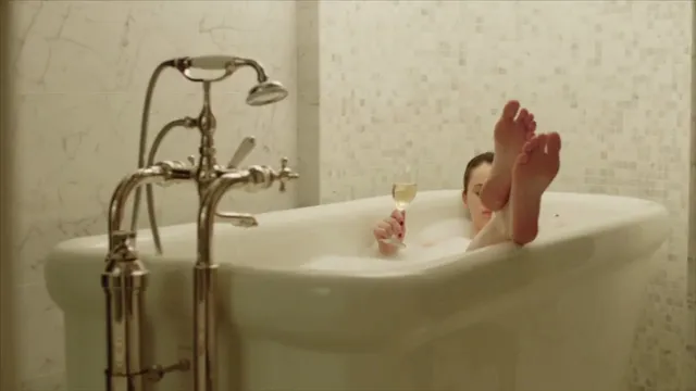 Felicity Jones relaxing in a freestanding bathtub in a screen scene.