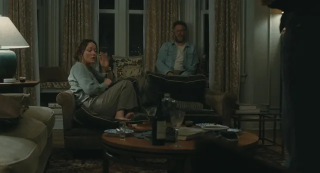Olivia Wilde sitting with other people around a table in a film scene.