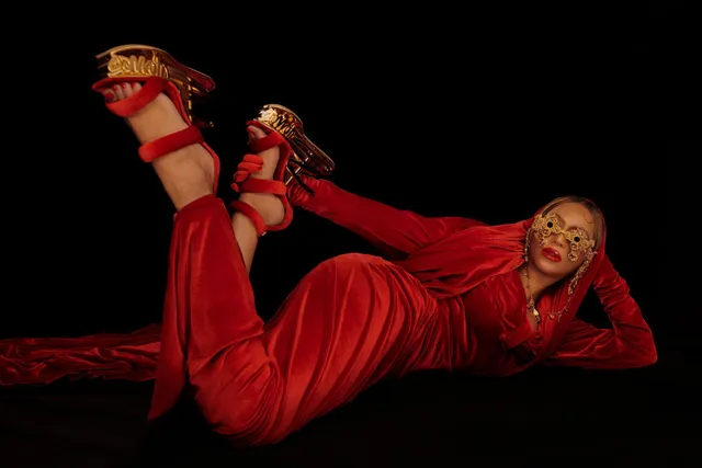Beyoncé reclining in a red outfit with platform heels raised.