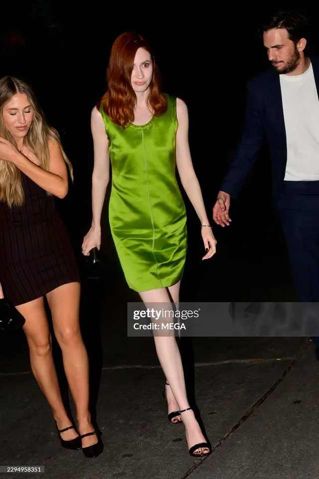 Karen Gillan walking with guests in a green dress and black heels.