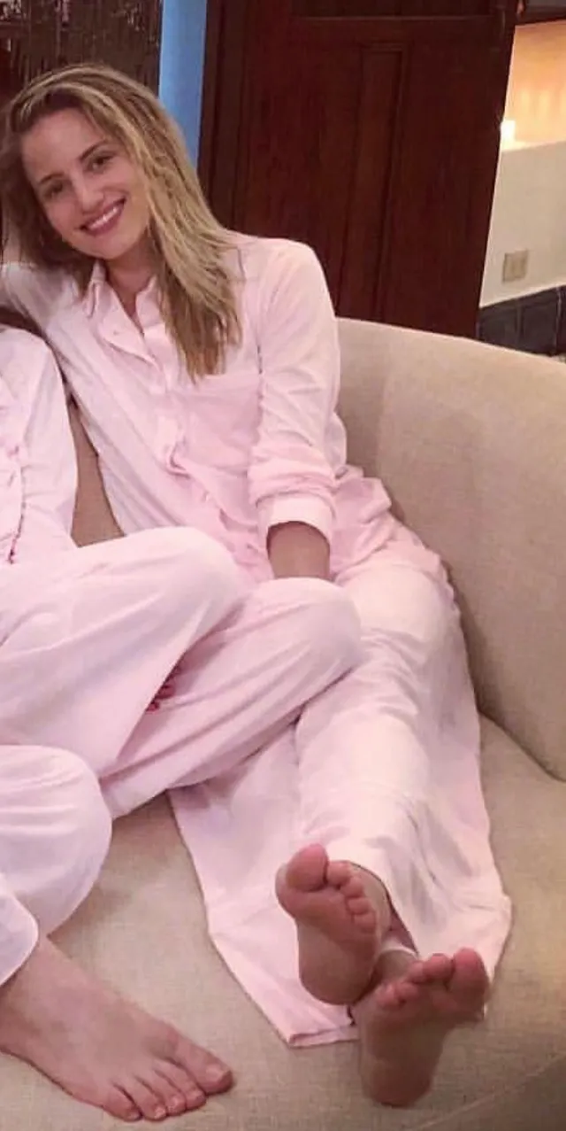 Dianna Agron relaxing on a sofa in pink pajamas.