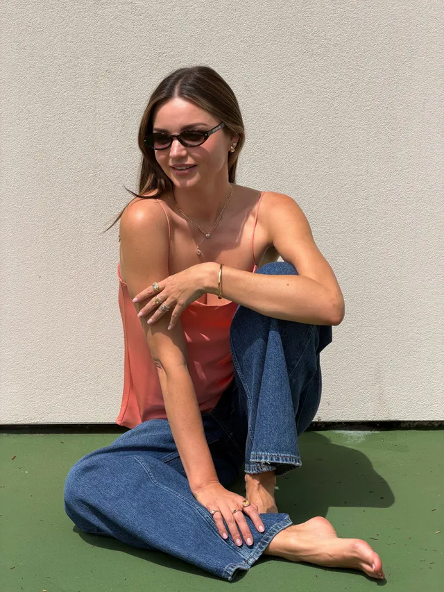 Miranda Kerr a seated denim portrait beside a pale wall.
