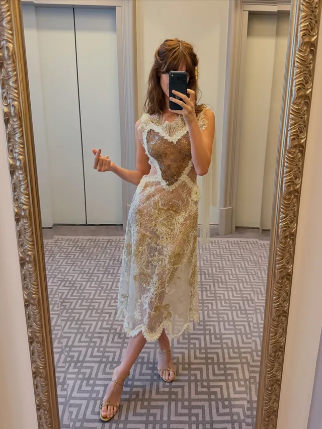 Daisy Edgar-Jones taking a mirror photo in a lace dress and heels.