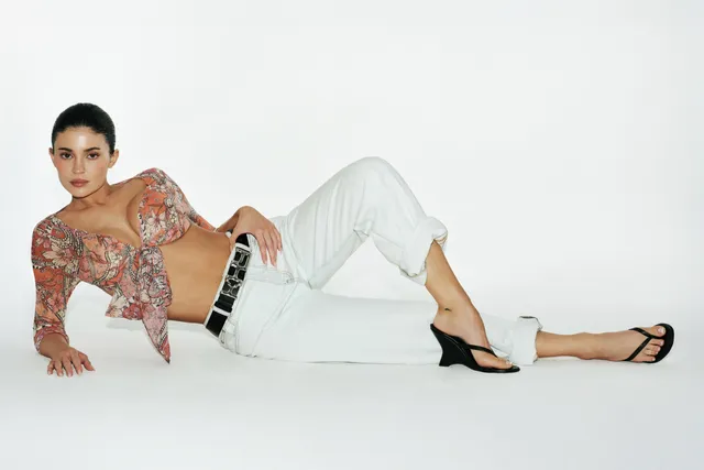 Kylie Jenner reclining in a studio portrait in black mule heels.