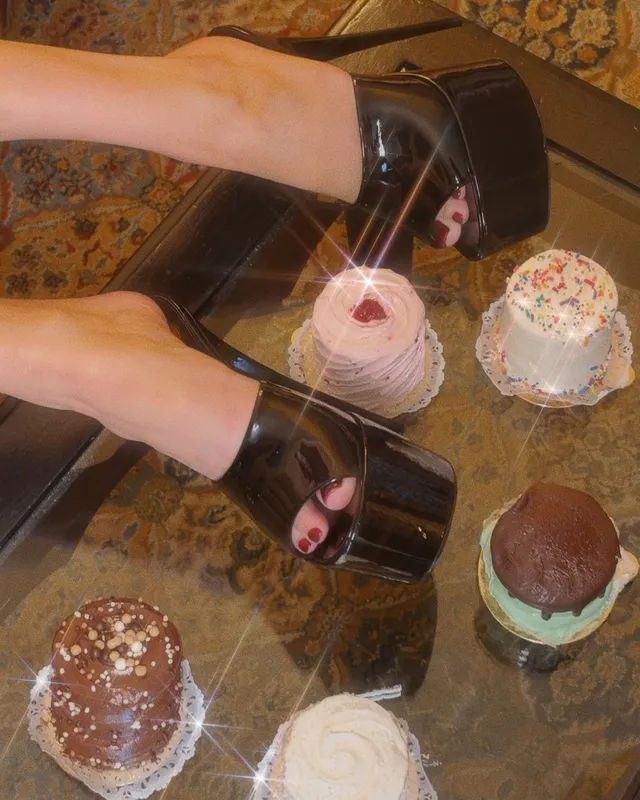 Bella Thorne a close view of black platform heels beside small cakes.