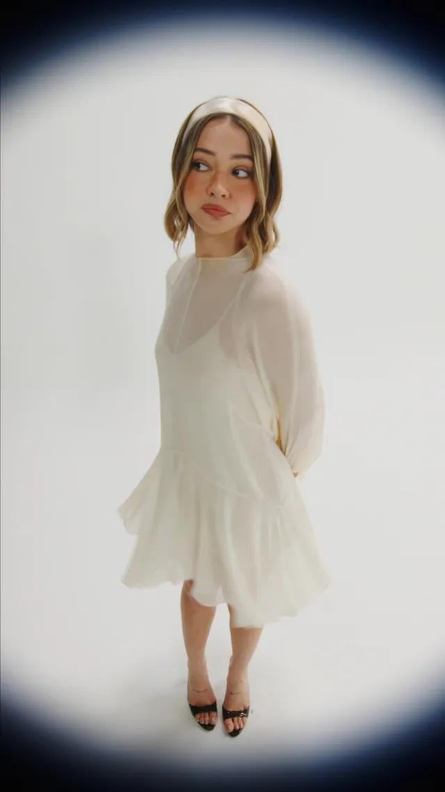 Madelyn Cline wearing a white outfit, headphones and black heels.