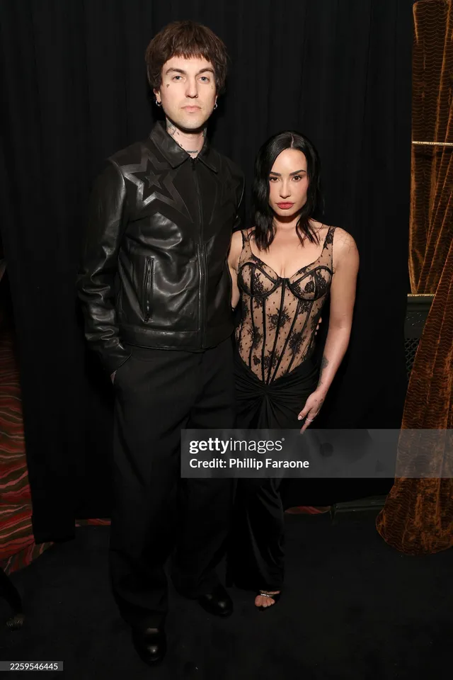 Demi Lovato posing beside another person in a black outfit.