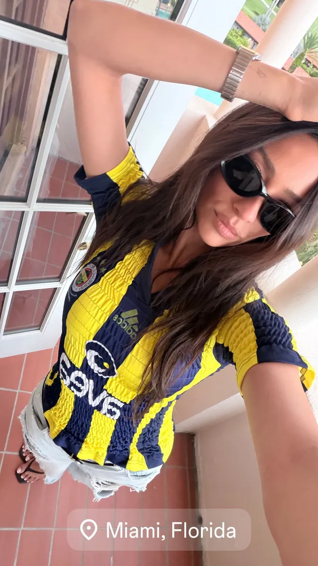 Shay Mitchell taking a balcony selfie in a sports jersey.