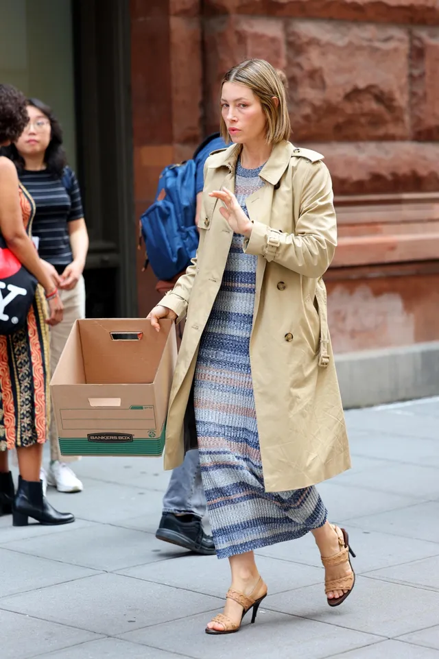 Jessica Biel walking outdoors in a coat and heeled sandals.