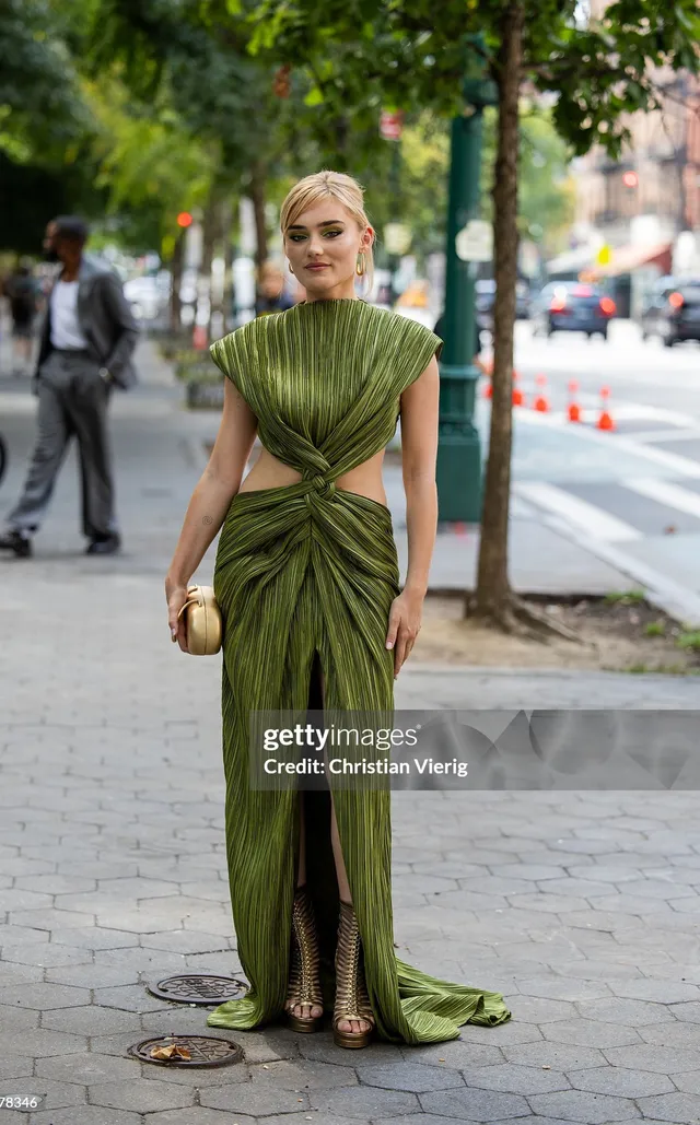 Meg Donnelly standing on a city sidewalk in a long green outfit.