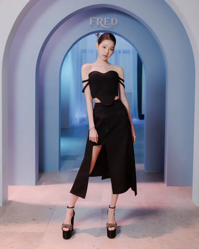 Jang Wonyoung posing in a black dress and platform heels at an event.