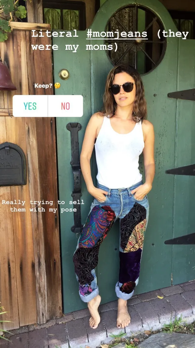 Rachel Bilson posing outdoors in a white vest and patchwork jeans.