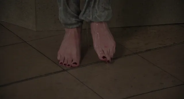 Lili Reinhart standing barefoot on a tiled floor in a screen detail.