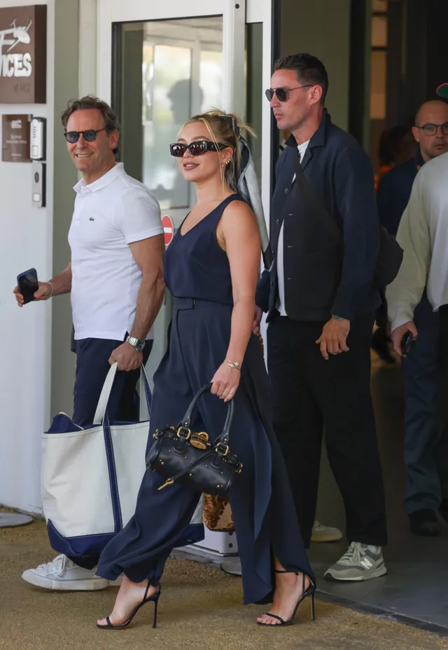 Florence Pugh walking in a navy outfit and black heels.