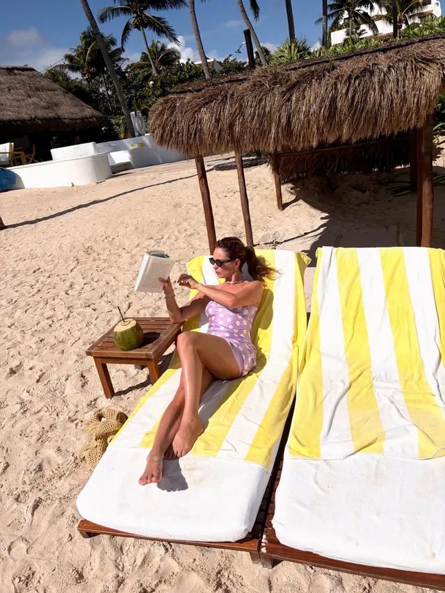 Lily James relaxing barefoot on a beach lounger.