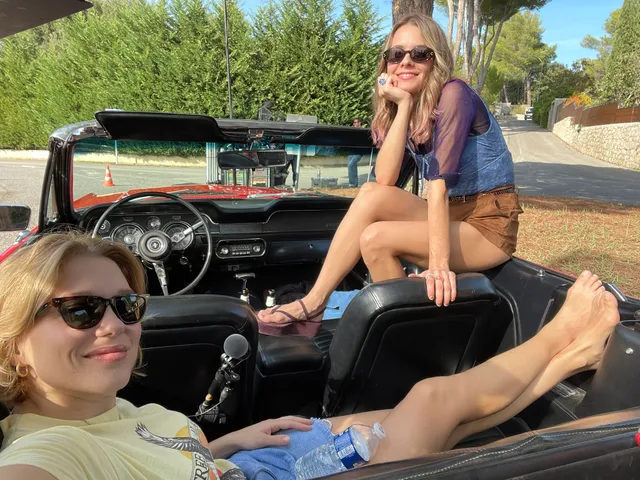 Léa Seydoux relaxing with a companion in a convertible car.