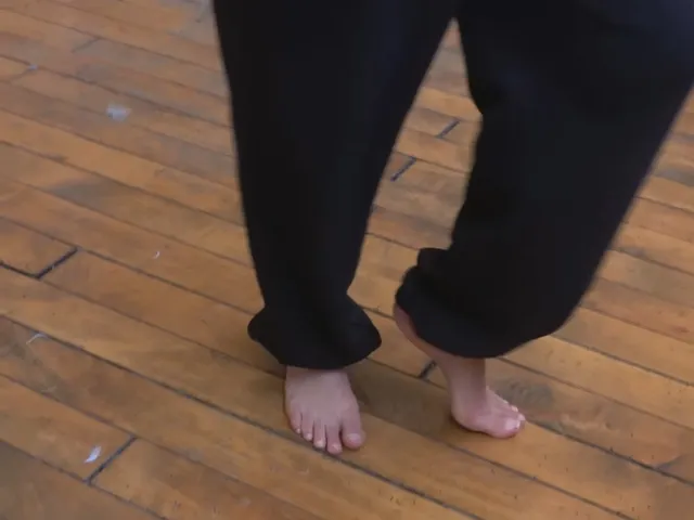 Naomi Scott standing barefoot on a wooden floor in a close detail.