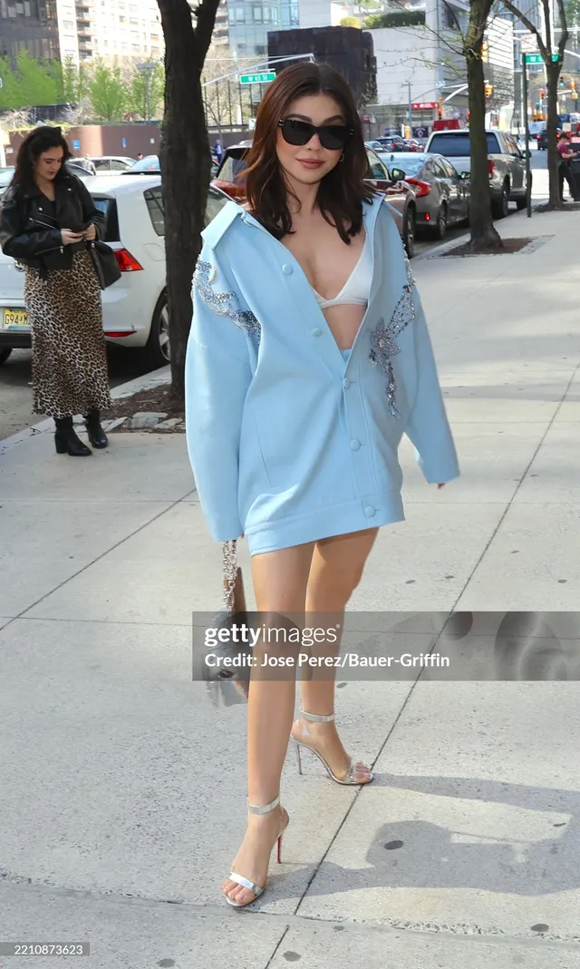 Sarah Hyland walking along a city pavement in a pale outfit.
