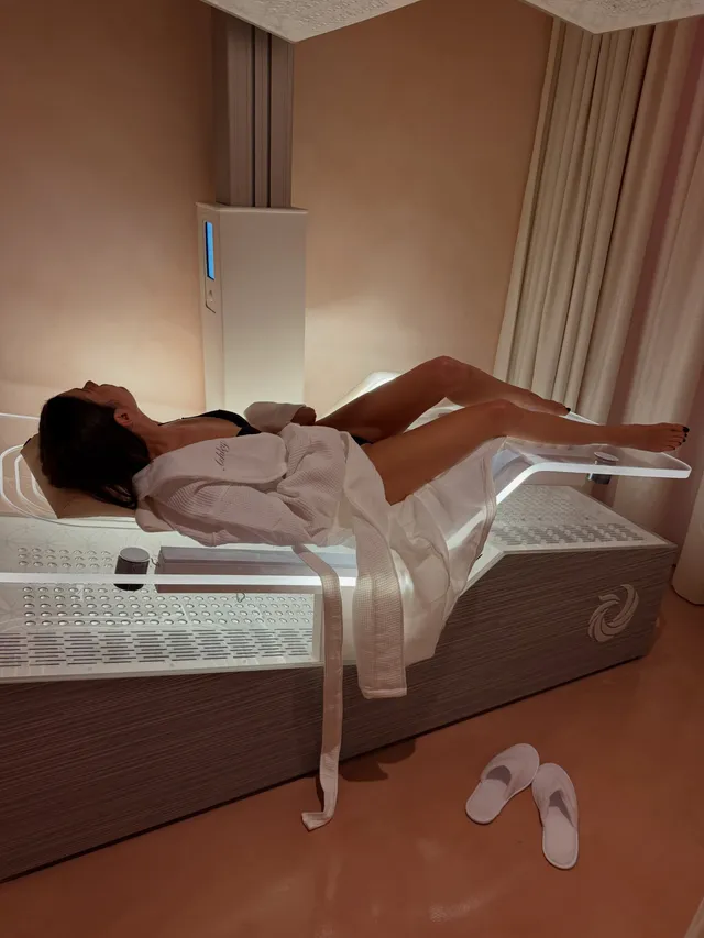 Ashley Benson reclining on a treatment bed in a robe.