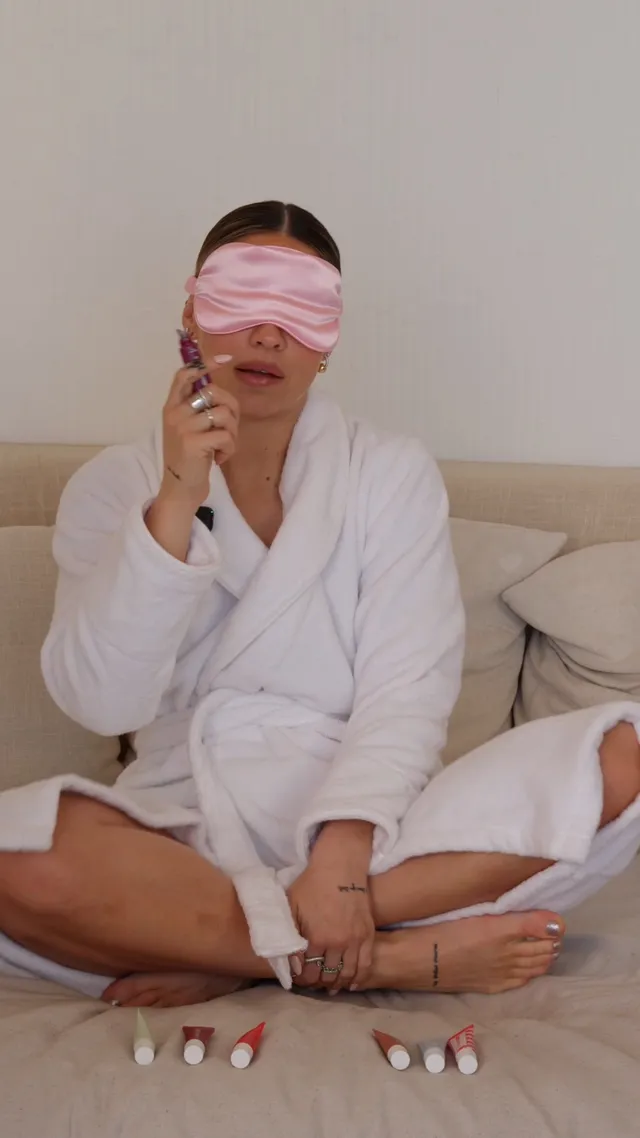 Madelyn Cline sitting cross-legged and barefoot in a white robe.