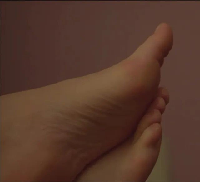 Léa Seydoux resting crossed feet in a warm lit screen scene.