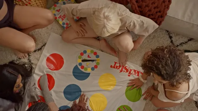 Billie Eilish playing Twister barefoot with friends indoors.