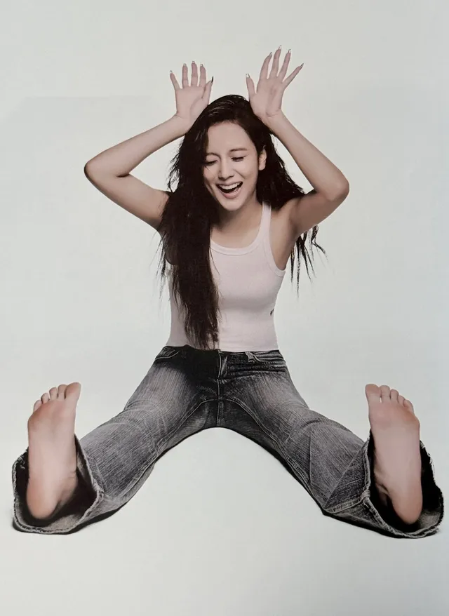 Jisoo sitting on a studio floor with her bare soles facing the camera.